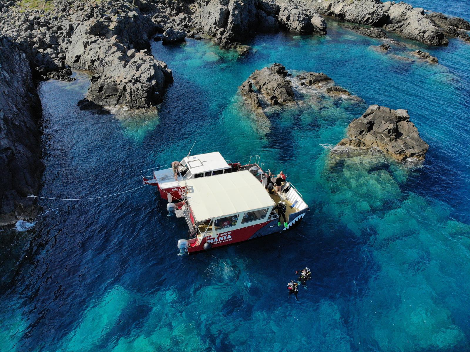 Aerial view of the Manta boat in a rocky cove on Vis